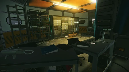 On a table, inside the white tent with servers and PCs, next to Weapon Testing area