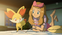 Serena en pijama leyendo con Fennekin.