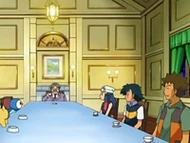 EP553 Tomando un té.png (75 kB) Salón de la mansión. El espacio está repartido mayormente en una larga mesa rectangular.