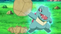 Totodile de Khoury usando fuerza bruta. Levanta una roca generando un aura...