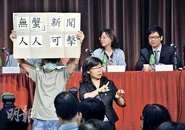 「事旦男」在廣管局第二場公聽會上，展示自製標語「『無蟹』新聞，人人可擊」。（明報圖片）