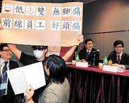 「事旦男」在廣管局第三場公聽會，展示自製標語「低志雙無腳痛，前綫員工好頭痛」。（星島日報圖片）