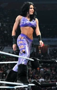 Melina smirking evilly while posing on the ring ropes