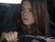 Nikki drives in a car targeting Tom