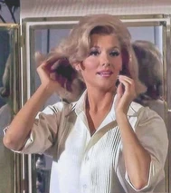 Barbara pivots away from the mirror to face Matt as he enters his bathroom.