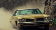 The Oldsmobile speeds down a dusty road while on the way to the cabin ()