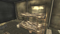 A sniper rifle lies on the center bunk in First Recon's tent