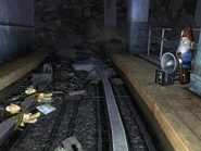 Гном и привязанные к рельсам метро плюшевые мишки (рядом табличка с надписью «Help us» — «Помоги нам»)