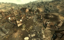 Ruined houses, mailbox to the right of the cars