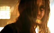 A scene from the trailer depicting Alma in a sunny warehouse, with a ray of light obscuring part of her face.