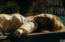 She hides from the soldiers, by the body of a young woman