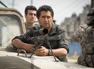 Castro watching as Travis shoots an infected.