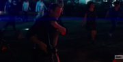 A policeman running with the crowd carrying an assault rifle