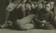 Posed sepia-toned photograph (apparently cropped from a team photograph) of Hughitt wearing a football uniform reclining on the floor