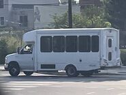 The 2016 Ford E-350 158" Dual-Rear Wheelbase Cutaway Van Exterior shown in Oxford White equipped with the High-Series Exterior Upgrade package with a Passenger Side Door Deleted and 16" x 6" White-Painted Steel Wheels used on Turtle Top Terra Transit Wheelchair-equipped Shuttle Buses