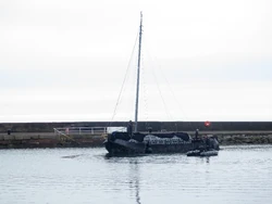 A partially covered armored boat in the harbor.