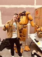 Dawko wearing the Yellow Rabbit's hands and standing next to the suit.