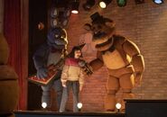 Piper singing into Freddy's microphone while Bonnie is behind playing the guitar.