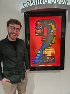 A photo of Kellen next to the Five Nights at Freddy's 2 poster.