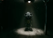 The creature, standing in a old version of the cabin.