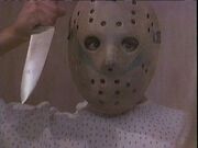 Giving in to his psychosis the hockey mask-clad Tommy attacks Pam Roberts with a knife.