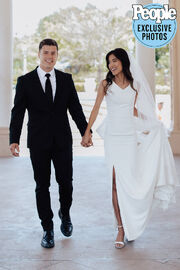 Lawson and Tiffany walking hand in hand in their wedding clothes, with Tiffany smiling at Lawson