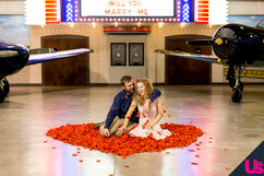 John and Abbie sitting in the midst of a heart of red petals