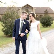 Justin and Claire walking along a path outside smiling at each other on their wedding day