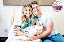 Alyssa and John sitting on the hospital bed holding baby Maci Jo in their arms