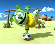Gummibär standing on a football ball with a hand.
