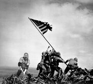 Triple H hoists his sledgehammer as troops hoist the American flag at Iwo Jima