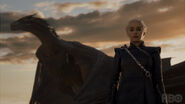 Drogon perched behind Daenerys.