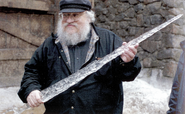George R.R. Martin handling a prop White Walker ice blade, during filming for Season 1.