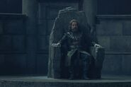Borros Baratheon sitting on the stone throne of Storm's End.