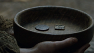 Square Braavosi coins return in the Season 6 premiere, appearing in blind Arya's begging bowl.