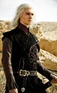 Viserys dresses in a style that was in fashion at the Targaryen royal court before Robert's Rebellion. The entire cut of the tunic is asymmetric, like a kimono. The outer coat is armless (but with peaked shoulder cuffs - perhaps meant to be reminiscent of a cobra's hood), fitting over a longer undercoat with close-fitting sleeves.