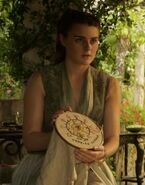 The Tyrell servants dress in fashions which imitate their leaders. This Tyrell lady's dress is also sleeveless with a plunging neckline. She also has Margaery's upswept hairstyle.