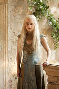 Growing dissatisfied with Qarth, Daenerys starts altering her outfits. This first hybrid design takes the heavy metal filigree from the wide belts worn in Qarth, and transforms it into a large armor-like piece extending around her chest and shoulders. Note her mother's ring on her left index finger.