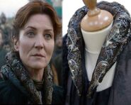 Closeup of the detailed embroidery on Catelyn's tall collar in Season 2, featuring Tully fish sigils.