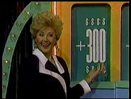 Aggie flashes another smile toward a contestant after uncovering a +$300 card