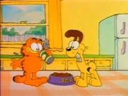 Dog Food Ingredients: Odie winces as Garfield reads fake dog food ingredients.