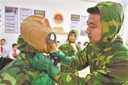 A personnel of the Civil Air Defense of China donning a TF-1 with the help of his comrade.
