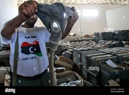 Libyan rebel holds up a black rubber ShM-41MU in an abandoned army warehouse