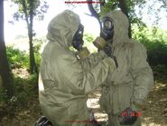 Soldiers helping each other with CBRN equipment