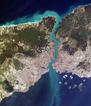 Satellite image showing a thin piece of land, densely populated on the south, bisected by a waterway