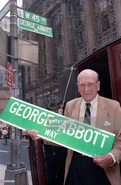George Abbott holds a copy of the street sign placed at the corner of W.45th Street and Broadway in his honor on the occasion of his 100th birthday