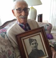 Aged 104, holding a photo taken during his military service