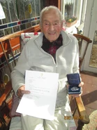 Crowley (aged 106; almost 107) on 7 May 2021, holding a letter and a silver medal he received from President Michael D. Higgins