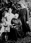 In 1935, wearing a white dress whilst accompanied by her mother (sitting), sister, and niece