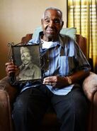 Aged 103, holding a photo of himself as a young man